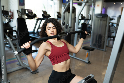 Pretty hispanic woman handling a gym machine