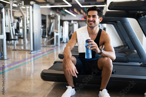 Fotografie Happy young hispanic man sitting on a treadmill