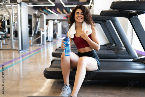 Young hispanic woman sitting on a treadmill