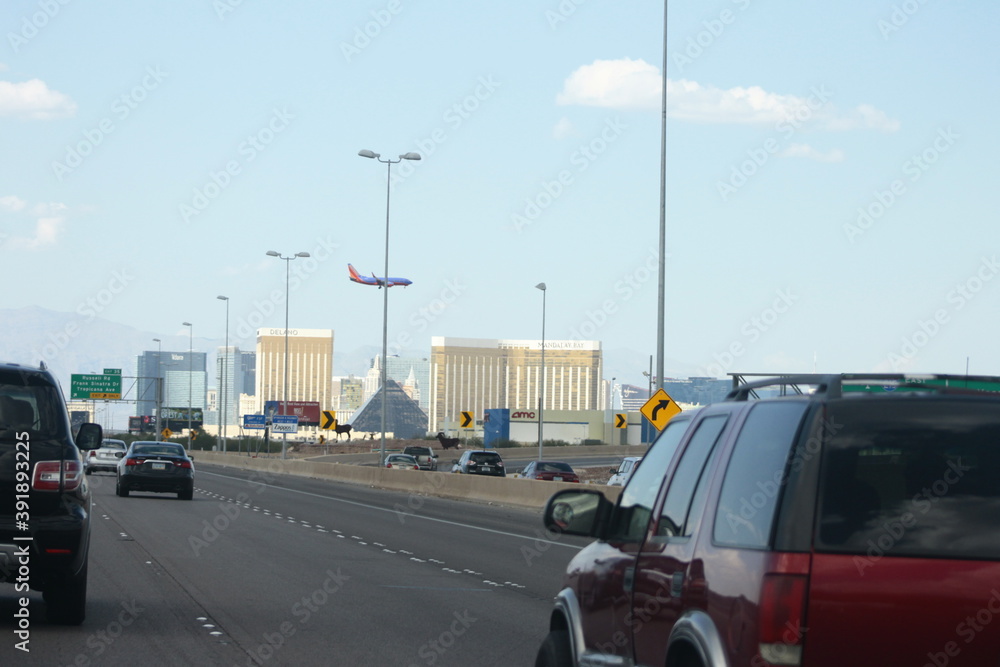 Las Vegas city entrance landscape with cars on freeway and airplane