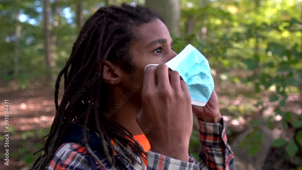 Young Gen Z Man Puts On Coronavirus Prevention Face Mask While Outdoors Young Gen Z Man Puts On Coronavirus Prevention Face Mask While Outdoors