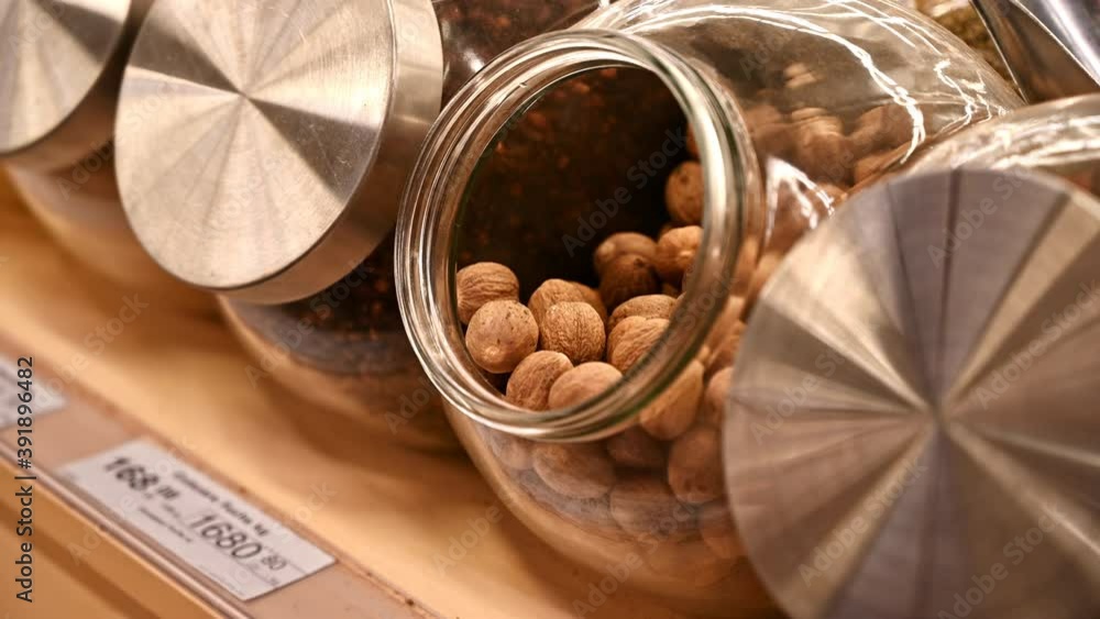 Man's hands unscrewing the lid of a jar with nutmegs and filling in another glass jar. Ecology idea Man's hands unscrewing the lid of a jar with nutmegs and filling in another glass jar. Ecology idea