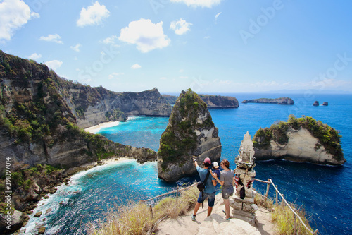 Young parents and little kid enjoying the views in Thousand Islands Viewpoint, on of the most amazing spots in Nusa Penida Island, Indonesia, Bali.