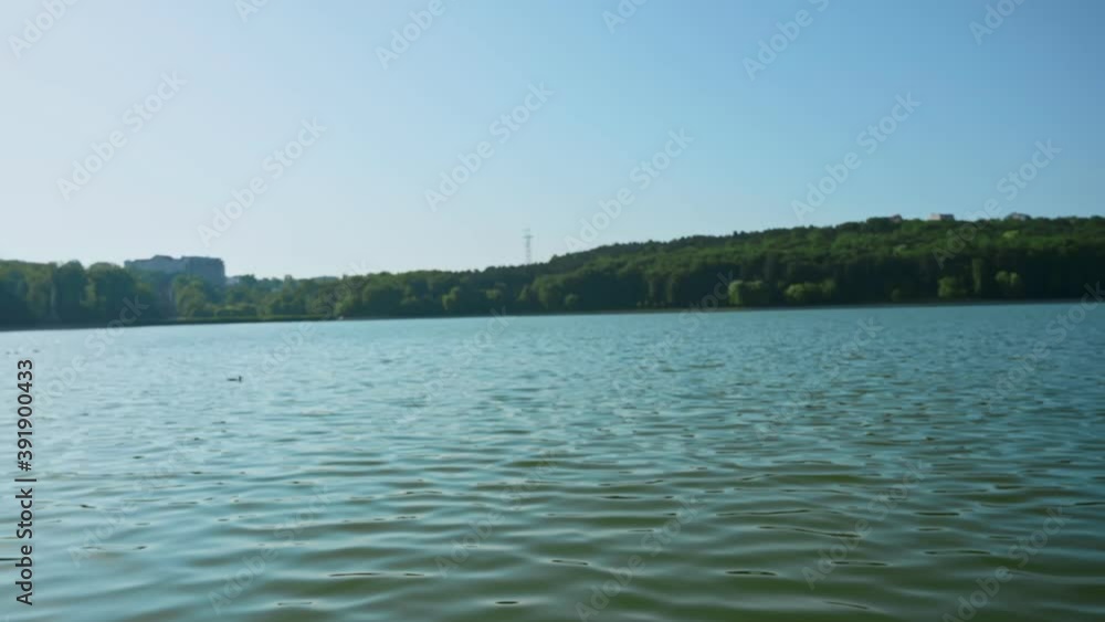 Young curly woman practicing yoga near the lake while wearing black protective mask. Sunny day. Meditating in lotus position on the yoga mat. Corona Virus idea Young curly woman practicing yoga near the lake while wearing black protective mask. Sunny day. Meditating in lotus position on the yoga mat. Corona Virus idea