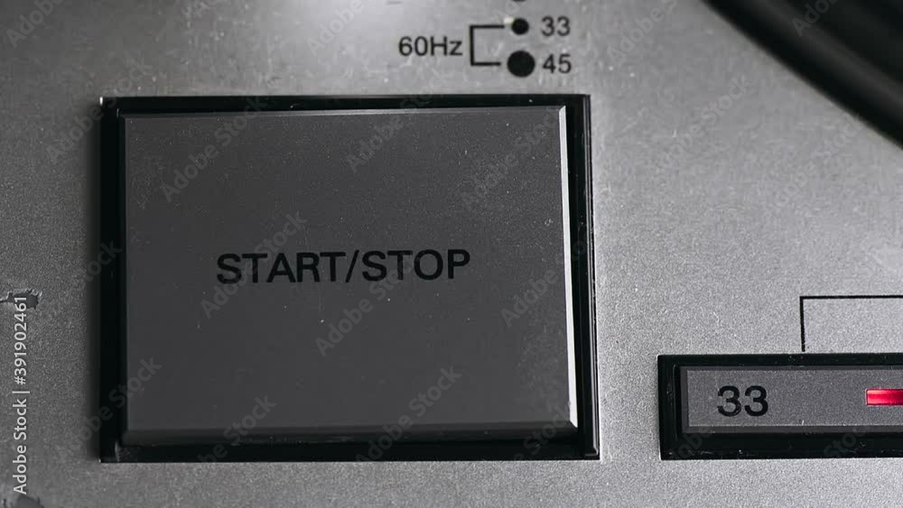 Pressing on button on vinyl player with turntable starting spinning Pressing on button on vinyl player with turntable starting spinning