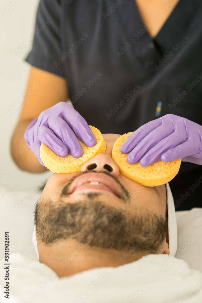 Limpieza facial de un hombre calvo en un spa, con fondo blanco y guantes  morados Photos