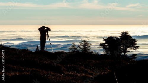 Silhouette of a photographer taking picture from a tripod early in the morning with good light on an inversion day.