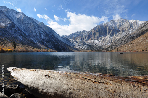 Pretty fall colors, snow-capped mountains, a big log and reflections at Convict lake on a cloudy day in the autumn