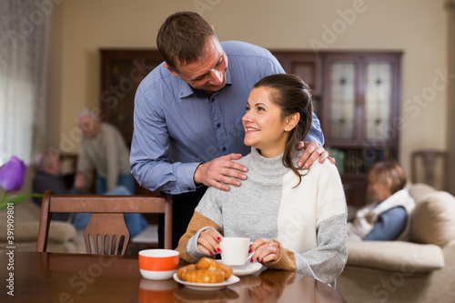 Happy couple hugging near living room table before drinking tea. High quality photo