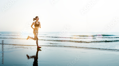Fotografie Sportive woman jogging at a beach