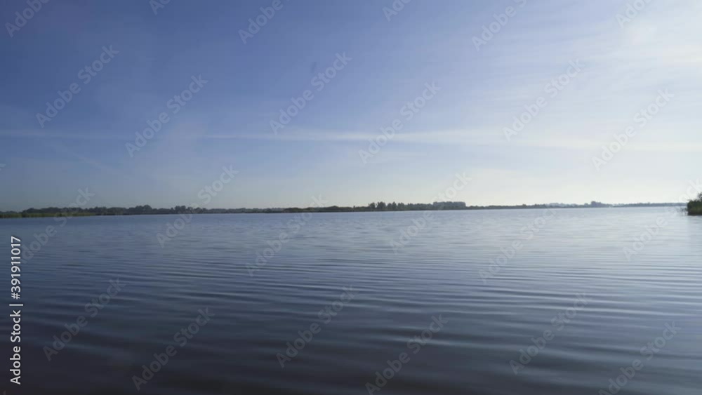 Shot of a lake in Friesland in Leeuwarden with view over the calm water lake for boats and sail ships, at a sunny day with a nice blue sky Shot of a lake in Friesland in Leeuwarden with view over the calm water lake for boats and sail ships, at a sunny day with a nice blue sky
