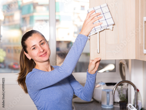 Smiling woman is cleaning surface on the kitchen at the home. High quality photo photo