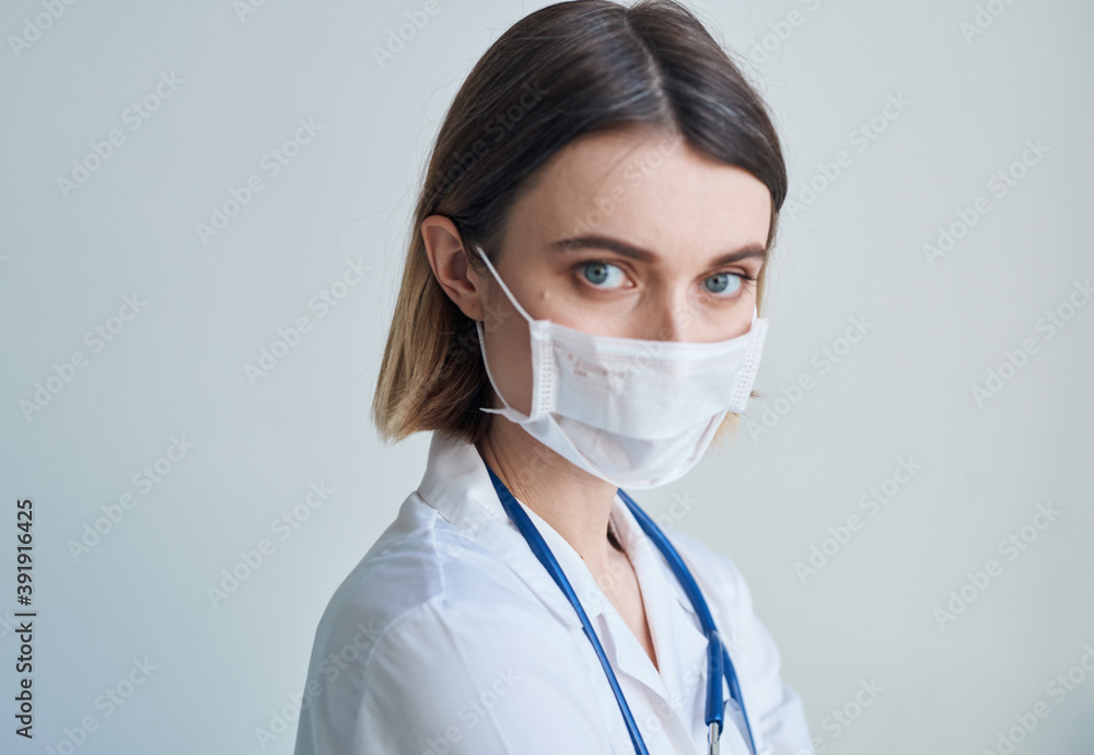 Woman doctor in a medical mask with a stethoscope around her neck