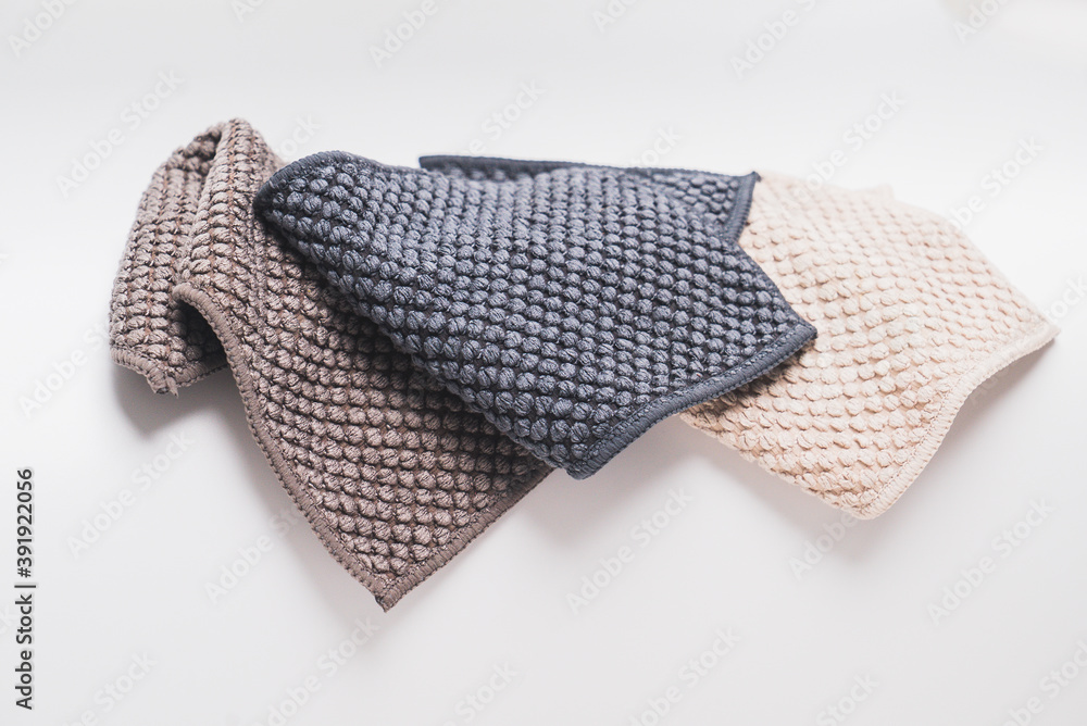 3 small kitchen towels, with recycled material in light brown, dark brown, and dark blue color. On the white background surface 3 small kitchen towels, with recycled material in light brown, dark brown, and dark blue color. On the white background surface