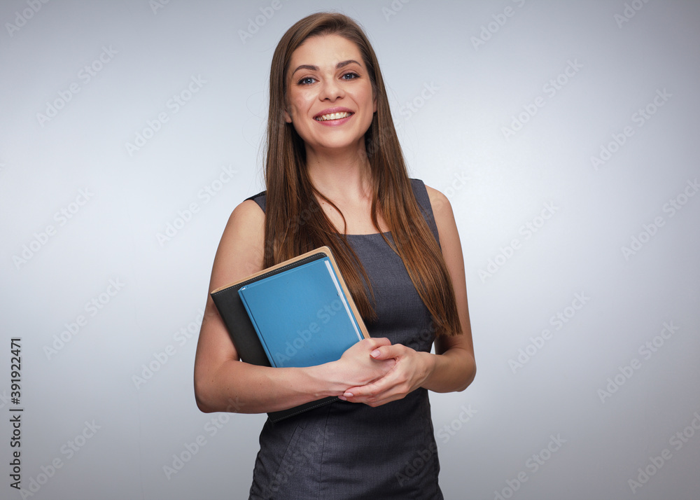 Smiling woman teacher in gray dress holding books. Smiling woman teacher in gray dress holding books.