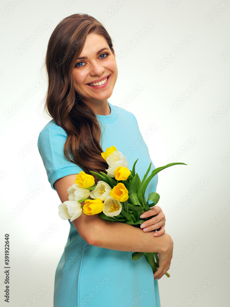 Smiling woman with long hair wearing blue dress holding yellow flowers. Smiling woman with long hair wearing blue dress holding yellow flowers.
