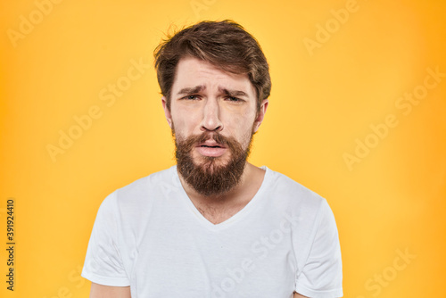A man in a white t-shirt gestures with his hands studio lifestyle yellow background emotions