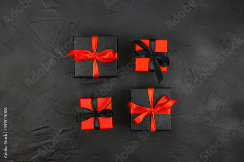 Set of black and red gift boxes with red and black ribbons on a black background. Holiday or black friday concept.