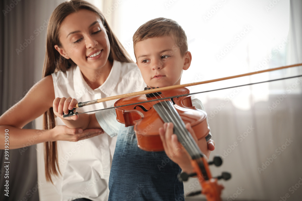 Young woman teaching little boy to play violin indoors Young woman teaching little boy to play violin indoors