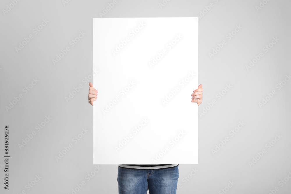 Man holding blank poster on light grey background - obrazy, fototapety, plakaty 