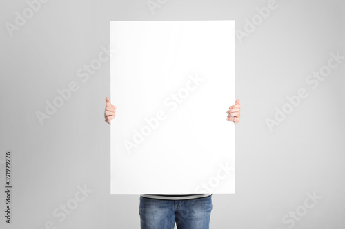 Man holding blank poster on light grey background