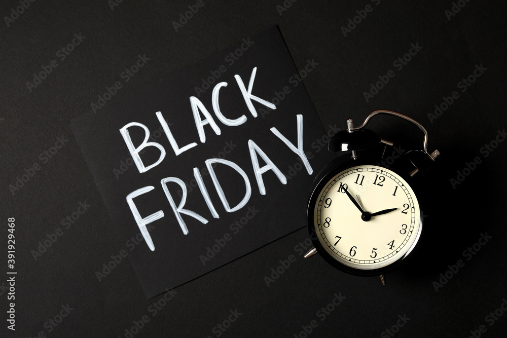 Phrase Black Friday and alarm clock on dark background, flat lay Phrase Black Friday and alarm clock on dark background, flat lay