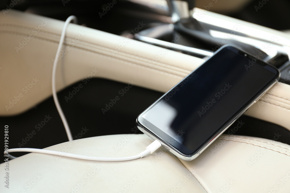 Mobile phone with charging cable in car, closeup