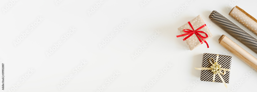 Web banner with two Christmas gits wrapped in kraft paper and paper rolls, top view, copy space Web banner with two Christmas gits wrapped in kraft paper and paper rolls, top view, copy space