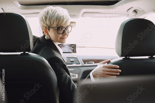 Businesswomanin a car. Lady in a black suit. © prostooleh