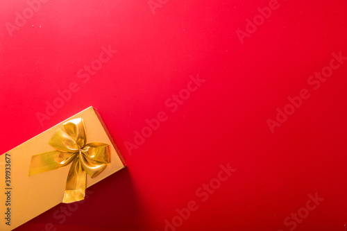 Gift in a golden package with a bow on a red background