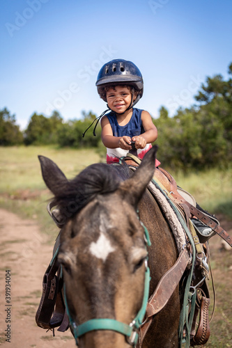 Cute, Smiling little boy riding on a horse. He is happy and enjoying his first pony ride at a mountain ranch