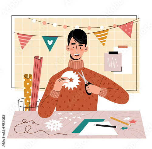 A young guy cuts out of paper. Hobby. Home leisure.