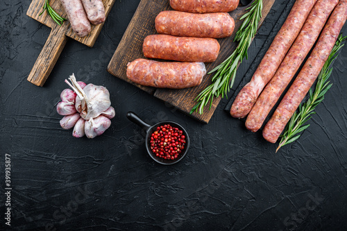 Raw sausages, top view with space for text, on black background