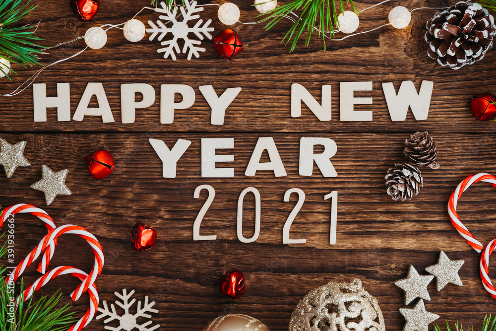 Wooden letters Happy New Year 2021 on a wooden background, next to toys on a Christmas tree, fir branches and Christmas lollipops. Greeting card. Wooden letters Happy New Year 2021 on a wooden background, next to toys on a Christmas tree, fir branches and Christmas lollipops. Greeting card.