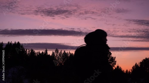 travel concept. black silhouette of a man in a hood against a purple sky. sunset in winter. travel in the winter forest photo