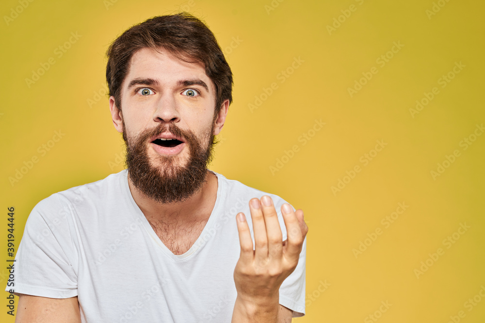 Bearded man in white t-shirt emotions close-up fun yellow background Bearded man in white t-shirt emotions close-up fun yellow background