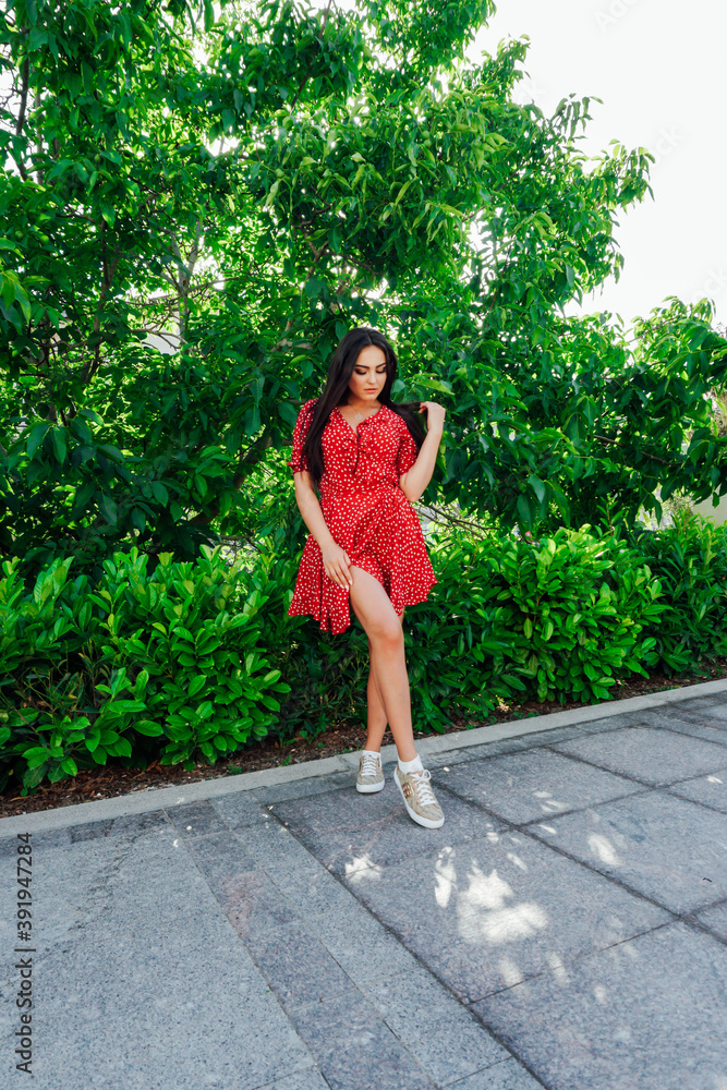 Beautiful brunette woman in red dress walks in the street Beautiful brunette woman in red dress walks in the street