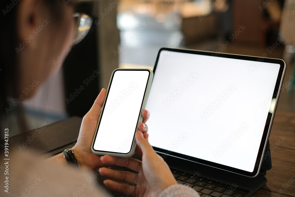 Cropped shot of a woman using smartphone and tablet with isolated white display in office.