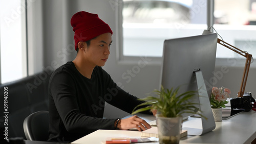 Portrait of freelance graphic designer sitting at his workspace and concentrate to working on computer.