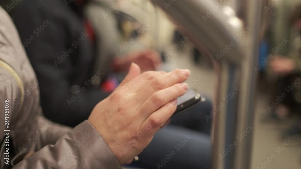 Close-up of female hands in the subway, typing a keyboard on a smartphone, sending a message, looking at photos, communicating on social networks Close-up of female hands in the subway, typing a keyboard on a smartphone, sending a message, looking at photos, communicating on social networks