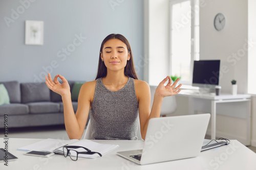 Calm business lady meditates with her eyes closed in her office during a break. © Studio Romantic