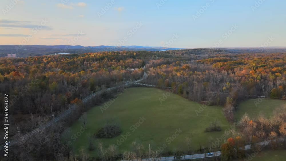 Flying over rural America at a four way intersection. There are fields, mountains, and colorful trees in the landscape and mountains in the background Flying over rural America at a four way intersection. There are fields, mountains, and colorful trees in the landscape and mountains in the background