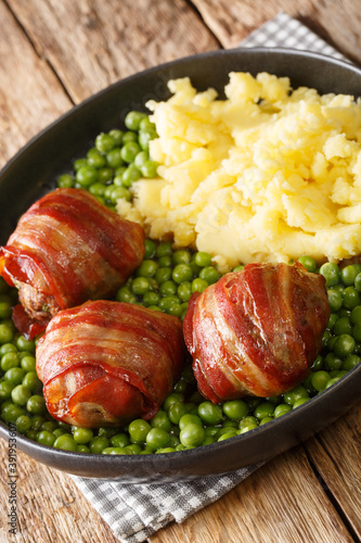 English food faggot meatballs garnished with green peas and mashed potatoes close-up in a plate on the table. vertical photo