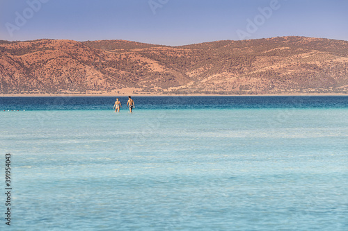 Fototapeta Naklejka Na Ścianę i Meble -  A couple in love walks in the azure shallow waters of lake Salda in Turkey.