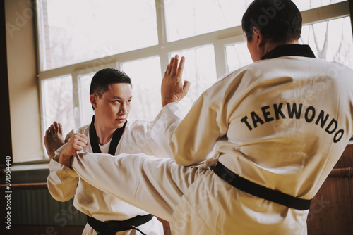 Two men practicing taekwondo together in the gym. 