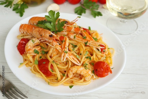 Italian Traditional Dish"Linguine with Scampi Shirmps",linguine with scampi,cherry tomatoes,white wine,olive oil,parsley,garlics and peppers on white plate with white table background