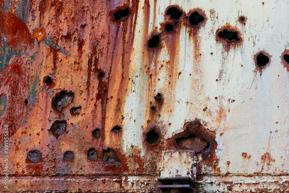 Old metal wall with through holes from bullet shots, rusty abstract horizontal background