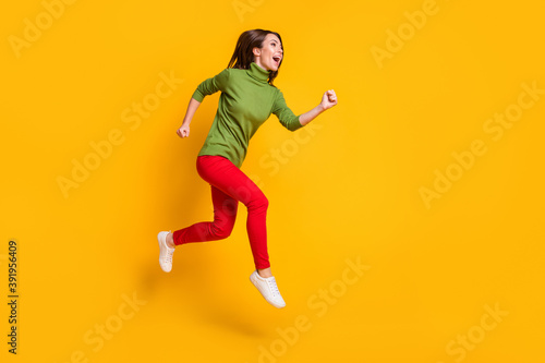 Lady jump up rushing excited wear casual green pullover shoes red trousers isolated yellow color background © deagreez