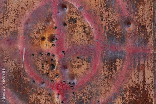 Rusty metal wall with through holes and a hunting target painted in paint