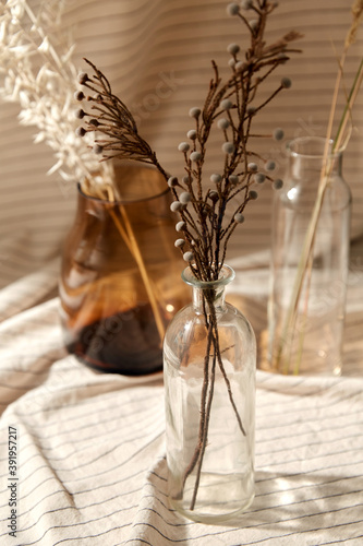 home improvement and decoration concept - still life of decorative dried flowers in glass vases and bottles with drapery